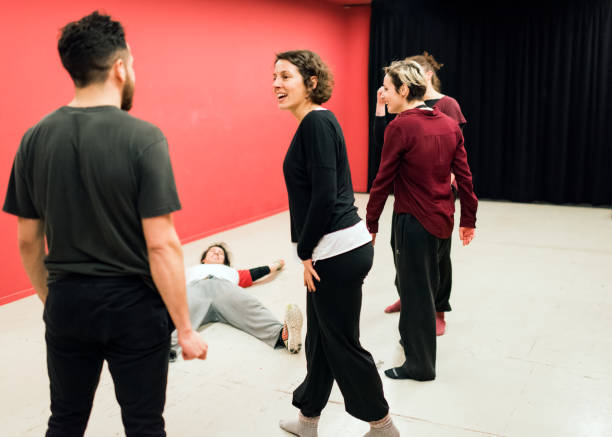 Theater students in class, one of them on the floor, surrounded by the others