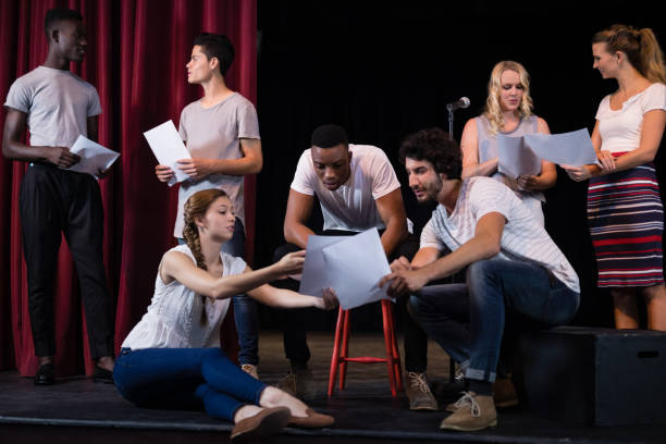 Actors reading their scripts on stage in theatre